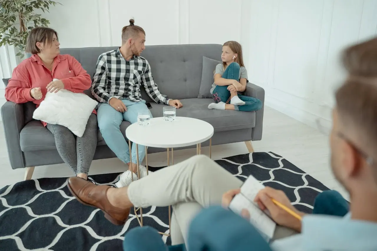Kanepede oturan bir aile ve önlerinde not alan terapist