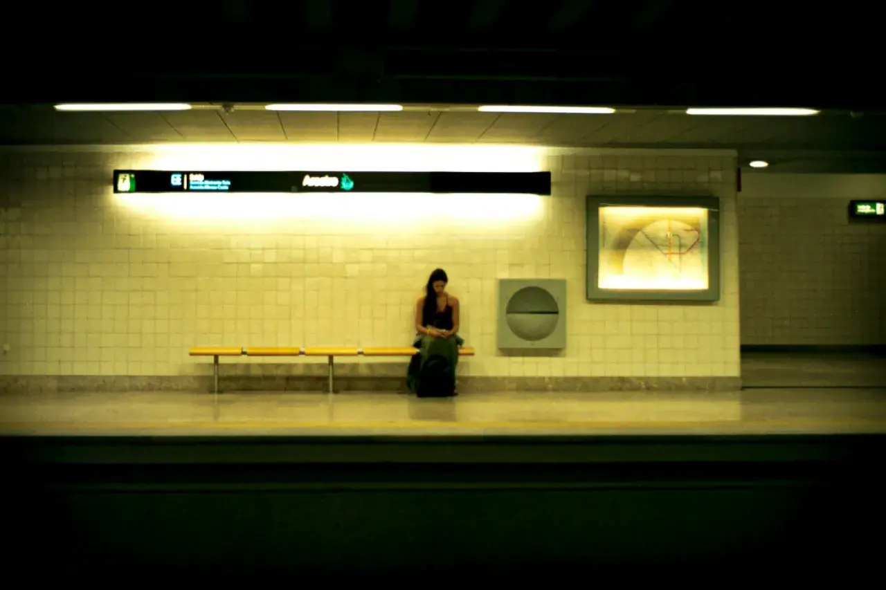 Loş bir metro istasyonunda bankta tek başına oturan genç bir kadın; panik atağın gündelik bir anda başlayabileceğini anlatan görsel