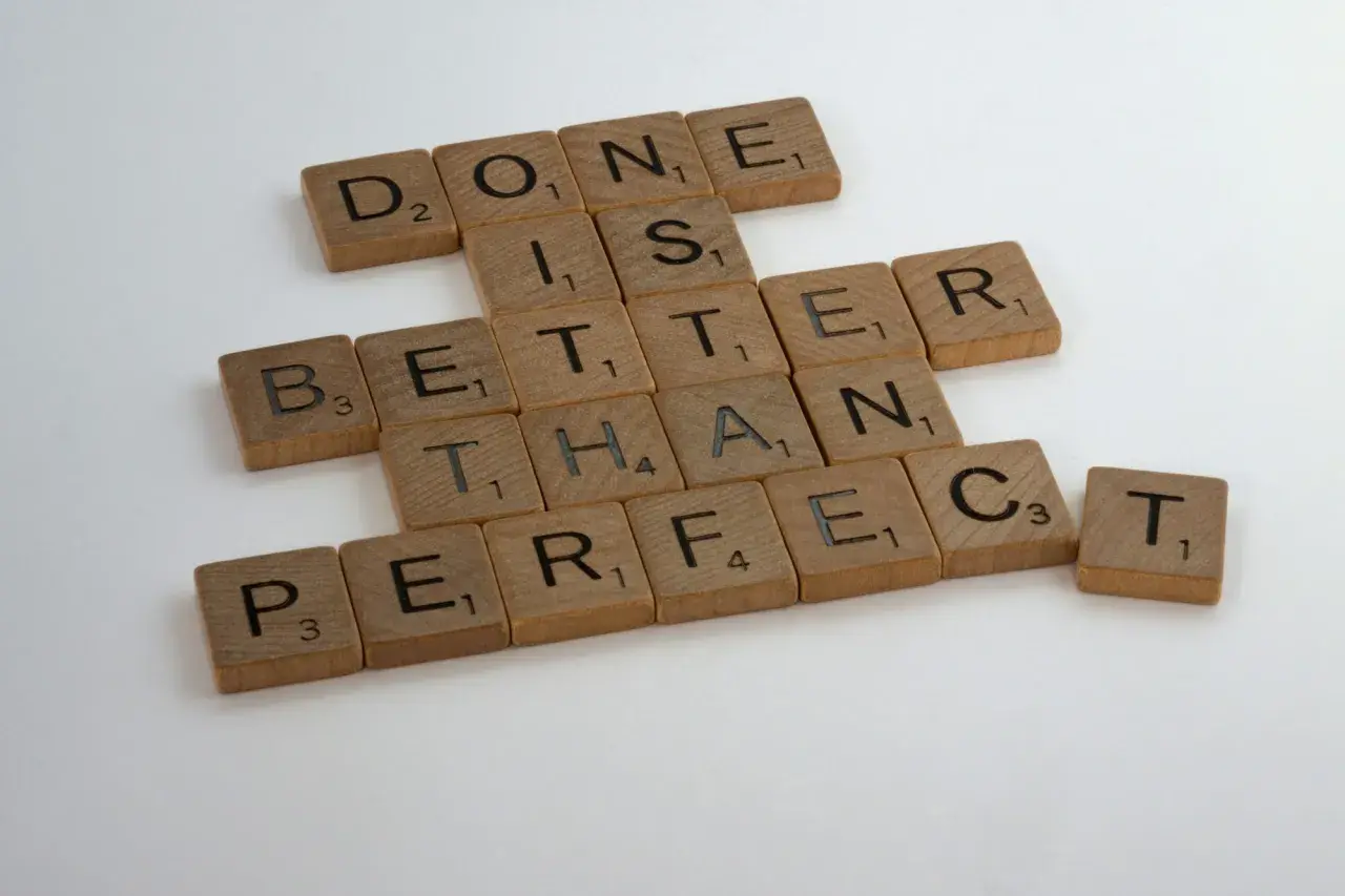 Beyaz zeminde "done is better than perfect" yazan ahşap harf blokları